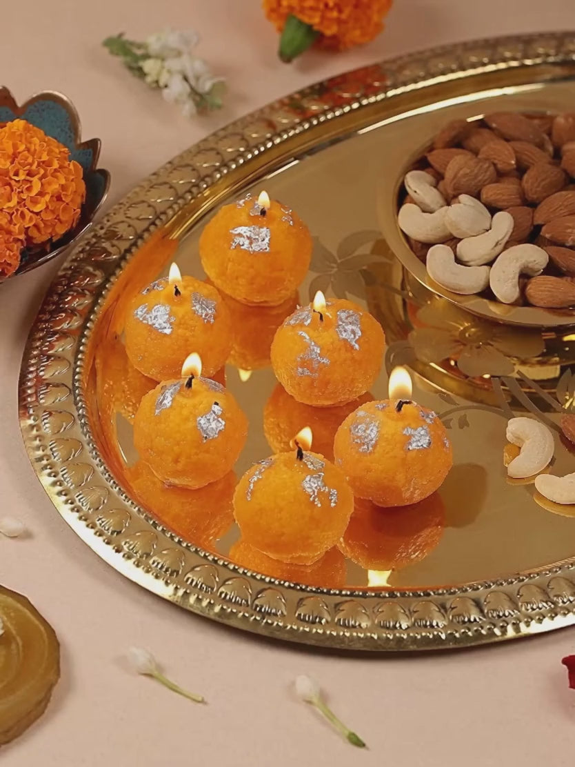 Motichoor laddu candles glowing on a thali
